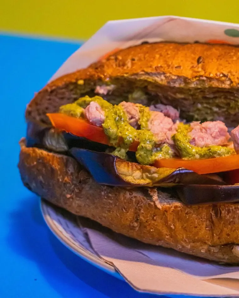 Dettaglio ravvicinato di un panino con melanzane grigliate, tonno e pesto